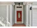 Inviting close-up of a red front door with a decorative glass insert and brick entryway at 7511 Savannah Ln, Tampa, FL 33637