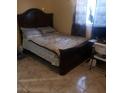 Cozy bedroom with a wooden bed frame, patterned linens, and tile flooring at 6718 Runningwoods Dr, Tampa, FL 33634