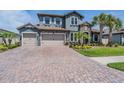 Beautiful home featuring a stone facade, tile roof, three-car garage, brick driveway, and well-manicured landscaping at 29043 Picana Ln, Wesley Chapel, FL 33543