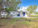 Backyard view of the light gray house, featuring blue door, and covered patio area at 8231 Riverside Ne Dr, St Petersburg, FL 33702