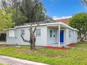 Exterior view showcasing the light gray house with solar panels and a blue door at 8231 Riverside Ne Dr, St Petersburg, FL 33702