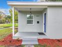 Inviting front porch with a blue door, overhead light, and well-maintained landscaping at 8231 Riverside Ne Dr, St Petersburg, FL 33702