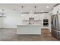 Bright kitchen featuring an island, white cabinets, stainless steel appliances, and modern pendant lighting at 1780 Draughton Dr, Zephyrhills, FL 33541