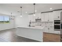 Bright kitchen featuring an island, white cabinets, stainless steel appliances, and modern pendant lighting at 1780 Draughton Dr, Zephyrhills, FL 33541