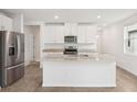 Modern kitchen with stainless steel appliances, white cabinets, and granite countertops on a central island at 1847 Brekey Way, Zephyrhills, FL 33541