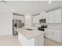 Modern kitchen featuring white cabinets, stainless steel appliances, and a large island at 1855 Brekey Way, Zephyrhills, FL 33541