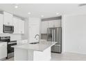 Bright, modern kitchen with stainless steel appliances, island, and sleek white cabinetry at 7728 Gilchrist Springs Dr, Parrish, FL 34219