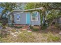 Exterior view of the back of house showing a blue door, window and overgrown yard at 9307 N Oakleaf Ave, Tampa, FL 33612