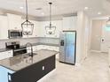 Modern kitchen boasts white cabinets, stainless steel appliances, granite countertops and island with stylish pendant lighting at 18875 Noble Caspian Dr, Lutz, FL 33558