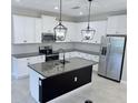 Contemporary kitchen featuring stainless steel appliances, island, granite countertops, white cabinets and decorative backsplash at 18875 Noble Caspian Dr, Lutz, FL 33558