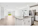 Kitchen with granite counters, stainless appliances, white cabinets and island, flowing into living area at 1740 Brekey Way, Zephyrhills, FL 33541