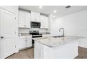 Bright kitchen with white cabinets, granite countertops, stainless steel appliances, and island at 1740 Brekey Way, Zephyrhills, FL 33541