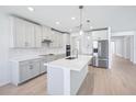 Bright, modern kitchen with white cabinets, stainless steel appliances, a central island, and light wood flooring at 1799 Draughton Dr, Zephyrhills, FL 33541