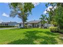 Charming single-story home with a lush green lawn, mature trees, and a quaint covered porch area at 2110 W Farwell Dr, Tampa, FL 33603