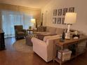 Bright living room featuring hardwood floors, modern sofa, and draped windows at 420 S Brockfield Dr, Sun City Center, FL 33573