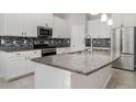 Modern kitchen featuring white cabinets, granite countertops, stainless steel appliances, and a stylish backsplash at 7308 Hermes Ct, Apollo Beach, FL 33572