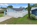 Side exterior view featuring a white fence, well-kept lawn, and light blue accents at 14506 Sutter Pl, Tampa, FL 33625