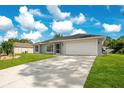 A single-story home with a well-manicured lawn and a two-car garage on a sunny day at 2706 Flagami Ln, North Port, FL 34286