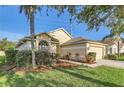 Well-maintained home featuring an attached garage, lush landscaping, and a charming front yard at 4305 Balmoral Ct, Wesley Chapel, FL 33543
