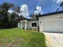 Modern single-story home featuring a well-manicured lawn, white exterior and an attached two-car garage at 353 Warrington Blvd, Port Charlotte, FL 33954