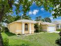 Well-maintained home exterior featuring a lush green lawn, manicured plants and bright yellow paint at 7337 Cone Shell Dr, Spring Hill, FL 34607