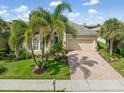 Charming single Gathering home featuring lush landscaping, manicured lawn, and a brick paver driveway at 13064 N Marsh Dr, Port Charlotte, FL 33953