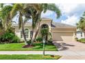 Charming single Gathering home featuring lush landscaping, manicured lawn, and a brick paver driveway at 13064 N Marsh Dr, Port Charlotte, FL 33953
