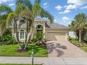 Charming single Gathering home featuring lush landscaping, manicured lawn, and a brick paver driveway at 13064 N Marsh Dr, Port Charlotte, FL 33953