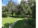 Expansive backyard with manicured lawn, mature oak trees, and white fence boundary at 17380 Sweetwater Rd, Dade City, FL 33523