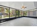 Spacious screened-in porch featuring a ceiling fan, ample natural light, and views of the backyard at 7214 Oakwood Dr, New Port Richey, FL 34652