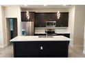 Modern kitchen with stainless steel appliances, dark wood cabinetry, and a center island with white countertop at 3269 Ponce De Leon Blvd, North Port, FL 34291