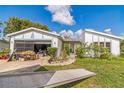Quaint home featuring white paint, gray trim, and a garage with a screened door at 18430 Alphonse Cir, Port Charlotte, FL 33948