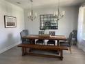 Elegant dining room with a wooden table, upholstered chairs, bench seating, and modern chandeliers at 302 Coco Plum Ct, Oldsmar, FL 34677