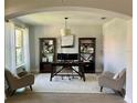 Inviting home office with dark wood desk, bookshelves, neutral chairs, and natural light at 302 Coco Plum Ct, Oldsmar, FL 34677