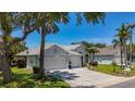 Charming single-story home featuring a three-car garage, a well-manicured lawn and mature trees and landscaping at 1913 Blue River Rd, Holiday, FL 34691