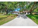 Spacious home with a concrete driveway, a red tile roof, and mature trees surrounding the property at 2504 Tanglewood Dr, Sarasota, FL 34239