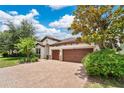 Beautiful home featuring a brick paver driveway, lush landscaping, and a tile roof, creating an inviting and picturesque curb appeal at 12784 Burns Dr, Odessa, FL 33556