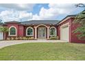 Elegant red home with arched windows, a paver pathway, lush lawn, and an attached two-car garage at 3244 55Th Ave N, St Petersburg, FL 33714