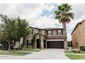 A two-story tan home with a well-manicured green lawn, tall trees, and an attached two-car garage at 9221 Mountain Magnolia Dr, Riverview, FL 33578
