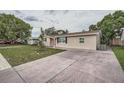 Side view of a single-story home featuring a concrete driveway, compact yard, and neutral exterior at 5429 Flora Ave, Holiday, FL 34690