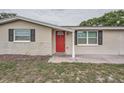 Close-up of the front exterior with a vibrant red door and tidy landscaping at 5429 Flora Ave, Holiday, FL 34690