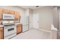 A clean kitchen featuring light wood cabinets and white appliances at 26622 Castleview Way, Wesley Chapel, FL 33544