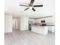 Open floor plan with kitchen, stainless steel appliances, and spacious living area with ceiling fan at 23461 Wickens Ave, Port Charlotte, FL 33980