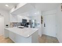 Bright white kitchen features stainless appliances and a breakfast bar with quartz countertop at 6210 Sun Blvd # 206, St Petersburg, FL 33715