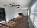 Spacious living room with wood flooring, a brick fireplace, a ceiling fan, and large windows at 1035 S Duncan Ave, Clearwater, FL 33756