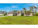 Inviting home with lush green lawn and palm trees, showcasing a well-manicured front yard and beautiful architecture at 14256 Salvatierra Ln, Port Charlotte, FL 33981
