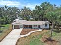 Aerial view showcasing a charming single-story home with a palm tree, a long driveway, and green surroundings at 14050 Blackjack Rd, Dover, FL 33527