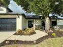 Inviting home exterior with landscaped pathway, black front door, and oversized tree providing ample shade at 19543 Midway Blvd, Port Charlotte, FL 33948