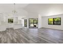 Open-concept living area with hardwood floors and plenty of natural light filtering through the large windows at 19543 Midway Blvd, Port Charlotte, FL 33948