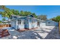 Side view of the house featuring a light blue exterior paint, concrete driveway and trimmed mulch beds at 6020 Illinois Ave, New Port Richey, FL 34653